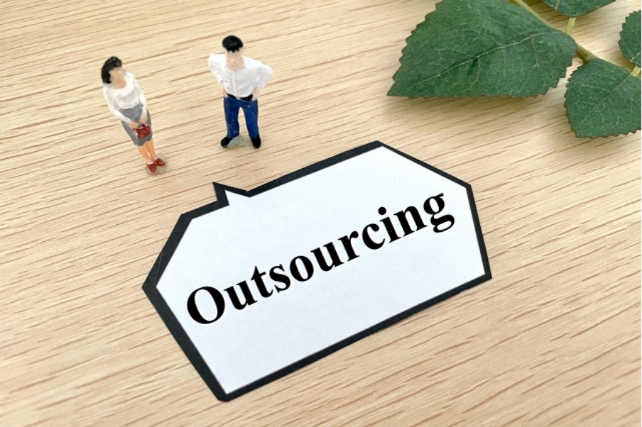 アウトソーシング（Outsourcing）の文字と人物のミニチュアフィギュア